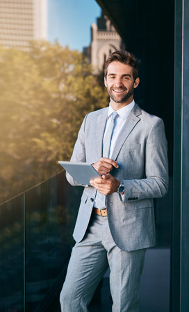 Business out in the open air. a handsome young businessman using a digital tablet outside an office building.の写真素材