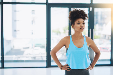 Work it out. a young fit woman standing and getting ready for a workout inside of a gym.の写真素材