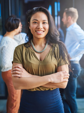 Business is my second language. Portrait of a young businesswoman standing on a balcony with her arms crossed.の写真素材