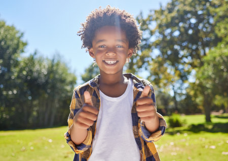 Happy child, portrait or boy with thumbs up in park for a fun activity or playing in nature or summer. Excited young African kid smiling on holiday outside with success, happiness or achievementの写真素材
