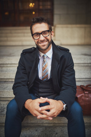 Expressions of style. Portrait of a stylish young man sitting on steps in the city.の写真素材