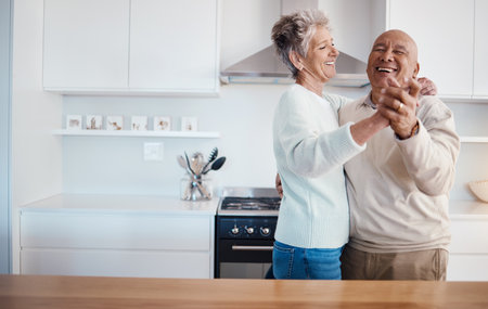 Love, retirement and dancing, old couple in kitchen at home, weekend time and celebrate romance with smile. Dance, happiness and bonding, happy man and senior woman having fun in house or apartment.の写真素材