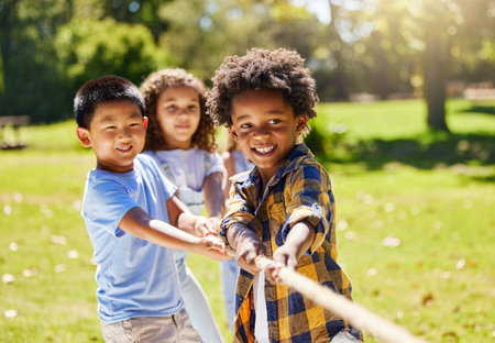 Fun, games and kids playing tug of war together outdoor in a park or playground in summer. Friends, diversity and children pulling a rope while being playful fun or bonding in a garden on a sunny dayの写真素材