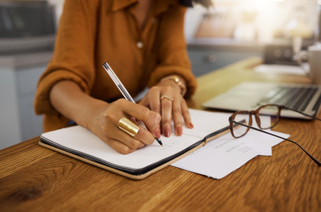 Closeup, writing and woman on laptop with documents for budget, savings and paying bills in her home. Paper, financial and future planning, investment and growth by female checking finance notesの写真素材