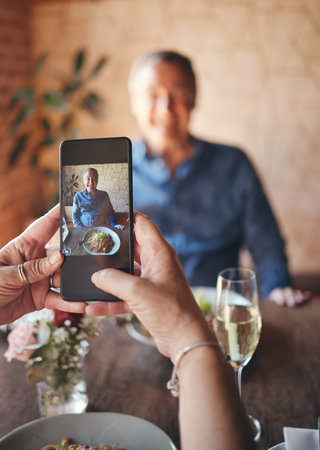 Happy man, phone screen and photograph in restaurant, cafe and fine dining lunch food for birthday, anniversary and dinner celebration. Couple coffee shop date, senior guy smile and mobile pictureの写真素材