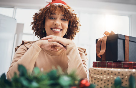 Christmas, gift or portrait and a business black woman posing with a box at an office party or event. December, holiday or present with a female employee sitting next to a giftbox while feeling happyの写真素材