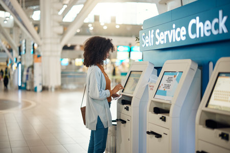 Black woman, airport and self service kiosk for check in, ticket registration or online boarding pass. African female traveler by terminal machine for travel application, document or booking flightの写真素材