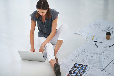 Shes a designer at heart. High angle shot of an attractive young businesswoman working on the floor in her office.の写真素材