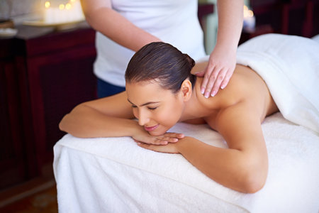 This is where you can actually make yourself at home. a young woman enjoying a back massage at a spa.の写真素材