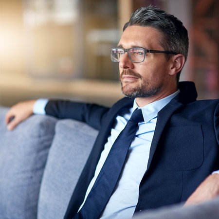 Hes a living success story. a businessman sitting on a sofa in an office.の写真素材