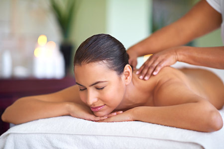 Well make you feel like you again. a young woman enjoying a back massage at a spa.の写真素材