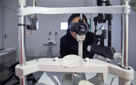 Optometry, healthcare and optometrist doing eye test in the clinic for eyecare and vision wellness. Medical, ophthalmology and muslim female optician doing optical exam with equipment at optic store.の写真素材