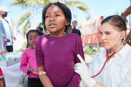 Take a big deep breath. a volunteer nurse examining a young patient with a stethoscope at a charity event.の写真素材