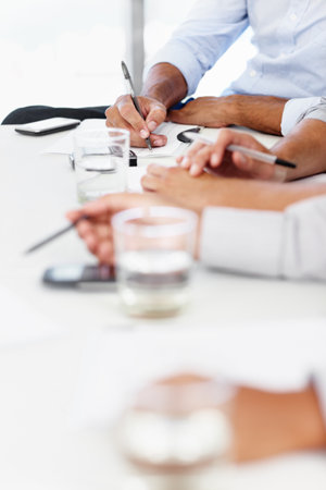 Boardroom details. a boardroom table with businesspeople sitting around it.の写真素材