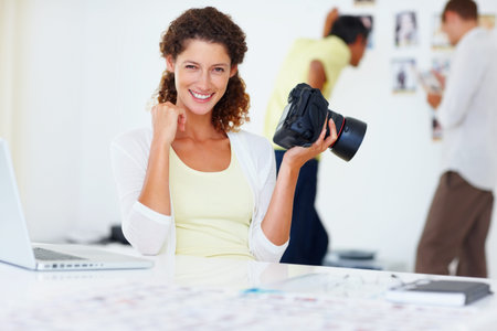 Female photographer smiling. Portrait of female photographer holding camera and smiling with...