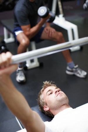 Working his pecs. two men lifting weights in the gym.の写真素材