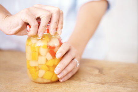 Making sure the lid is tight and secure. Cropped image of a woman opening a jar in the kitchen.の写真素材