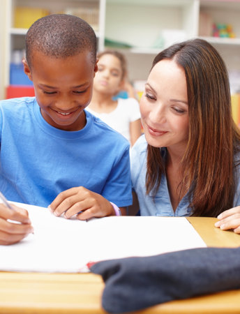 Can you show me how to get that answer. A pretty young teacher helping a student with his schoolwork.の写真素材