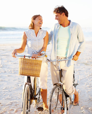 Out for a relaxing bike ride. A mature couple enjoying a bike ride on the beach together.の写真素材