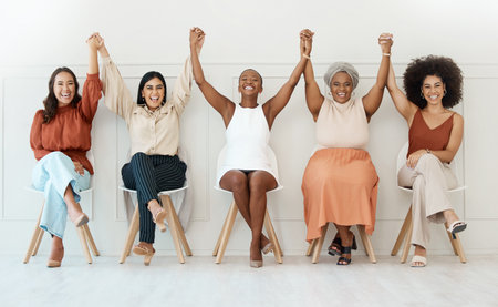 Happy women, business and teamwork celebration in waiting room for hiring, job opportunity or success at office. Group of woman employees holding hands in happiness for team win or victory in a rowの写真素材