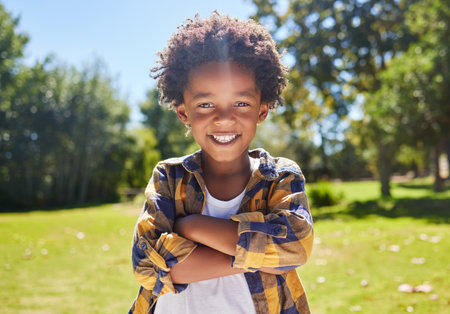 Portrait, arms crossed and black kid in nature, smile and vacation outdoor. Face, happiness and confident boy or child from South Africa having fun or enjoying summer holiday travel at park or gardenの写真素材