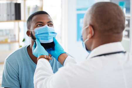 Doctor, check throat and patient with covid in hospital for symptoms, examination and consultation. Healthcare, black man and medical professional with face mask for treatment or checkup in clinicの写真素材
