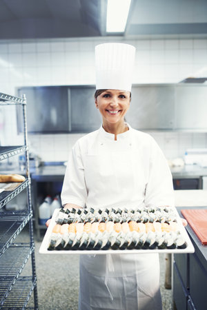 All you can eat. Portrait of a chef holding a large platter of sushi in a restaurant kitchen.の写真素材