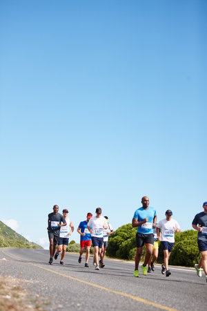 Enjoying the freedom of the road. a group of young men running a marathon.の写真素材