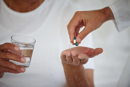 The doctors orders. Closeup shot of a senior patient getting his medication from a doctor while holding a glass of water.の写真素材