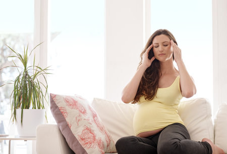 Feeling the discomfort of pregnancy. a young pregnant woman suffering with a headache.の写真素材