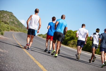 Company on the long run. Rearview shot of a group of men running a marathon.の写真素材
