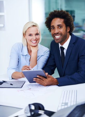 Feeling great about our future. Portrait of smiling colleagues in their office while using a digital...