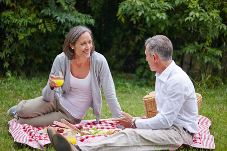 Still very much in love. a loving mature couple having a picnic on the grass.の写真素材