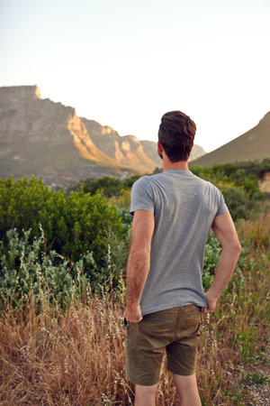 Sometimes you just have to take a moment. a handsome young man enjoying the view while hiking.
