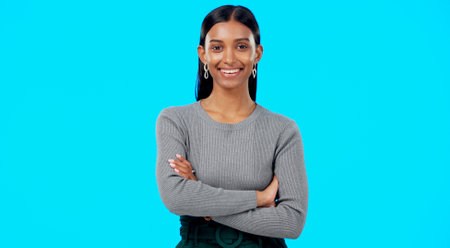Smile, confident and portrait of businesswoman arms crossed excited, proud and isolated in a studio blue background. Leader, professional and female with a positive mindset relax, calm and happyの写真素材