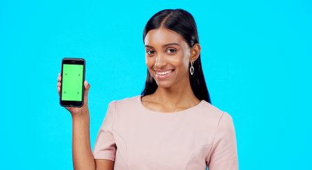 Chroma key, green screen and woman holding phone with mockup for logo, branding and mobile app advertising. Smile, happy and portrait of professional female isolated in a studio blue backgroundの写真素材
