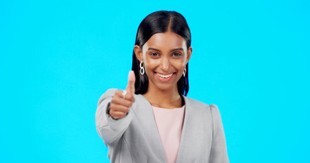 Thumbs up, perfect and happy businesswoman doing accept hand gesture, sign or symbol with smile. Excited, agreement and portrait of female showing approval isolated in blue studio backgroundの写真素材