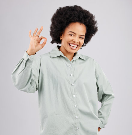 Happy, perfect and portrait of a black woman with a sign isolated on a white background in studio. Smile, ok and an African girl with a hand gesture for success, agreement and happiness on a backdropの写真素材