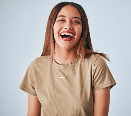Happy, laughing and portrait of a cheerful woman isolated on a white background in studio. Smile, funny and a beautiful young girl with happiness, smiling and positivity on a backdrop for expressionの写真素材