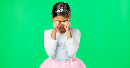 Sad, depression and child crying on green screen with crown, princess costume and tutu in studio. Sadness mockup, tears and isolated young girl with worried, upset and disappointed facial expressionの写真素材