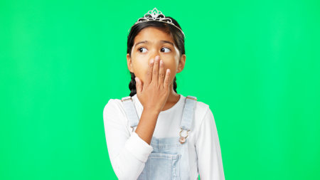 Girl, princess and shock face by green screen studio with wow, surprise and thinking in fantasy mock up. Female child, confused portrait and wonder with, tiara, mystery and hands on mouth for mockupの写真素材