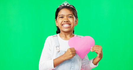 Portrait, heart and emoji with a girl on a green screen background for the celebration of valentines day. Kids, happy and love with a cute little female child holding a cardboard shape on chromakeyの写真素材