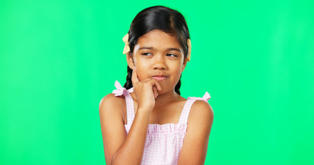 Thinking, green screen and idea by child with a question feeling excited, thoughtful and isolated in studio background. Planning, girl and joyful kid is happy, curious and planning expressionの写真素材
