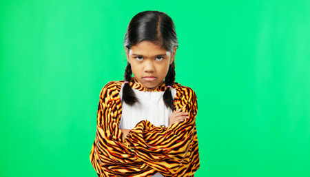 Girl child, angry face and green screen studio with arms crossed, refuse or shake head in tiger pyjamas. Frustrated kid, anger or portrait for mock up with mad, tired or bored expression by backdropの写真素材