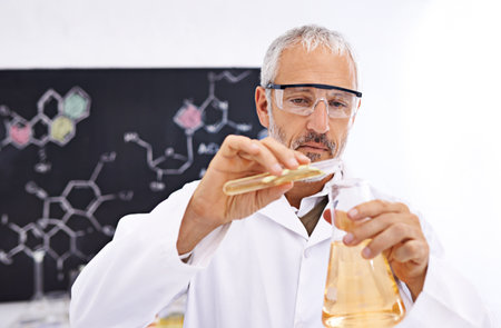 Lets see what happens...a mature male scientist conducting an experiment in his lab.の写真素材