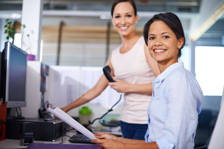 New project Bring it on. Portrait of a young businesswoman at her workstation with her colleague in the background.の写真素材