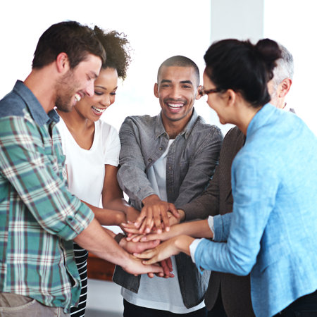 Lets get this done team. a group of positive coworkers standing in a huddle in an office.の写真素材