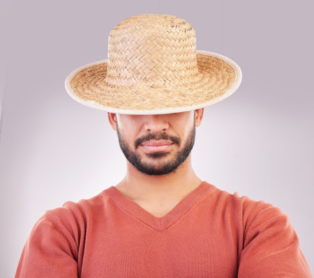 Man, hat and face in fashion style, hidden identity or profile standing isolated against a white studio background. Casual male model posing and wearing straw cap or stylish accessory covering eyesの写真素材