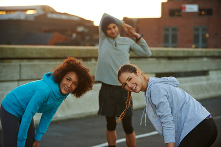 Lets get this run started. Portrait of three joggers warming up for an early run through the city.の写真素材