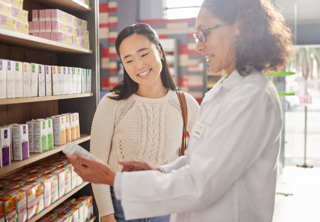 Dispensary, medication or prescription with a pharmacist and asian woman customer talking about a product. Healthcare, consultant and a medicine professional talking to a happy female in a pharmacyの写真素材